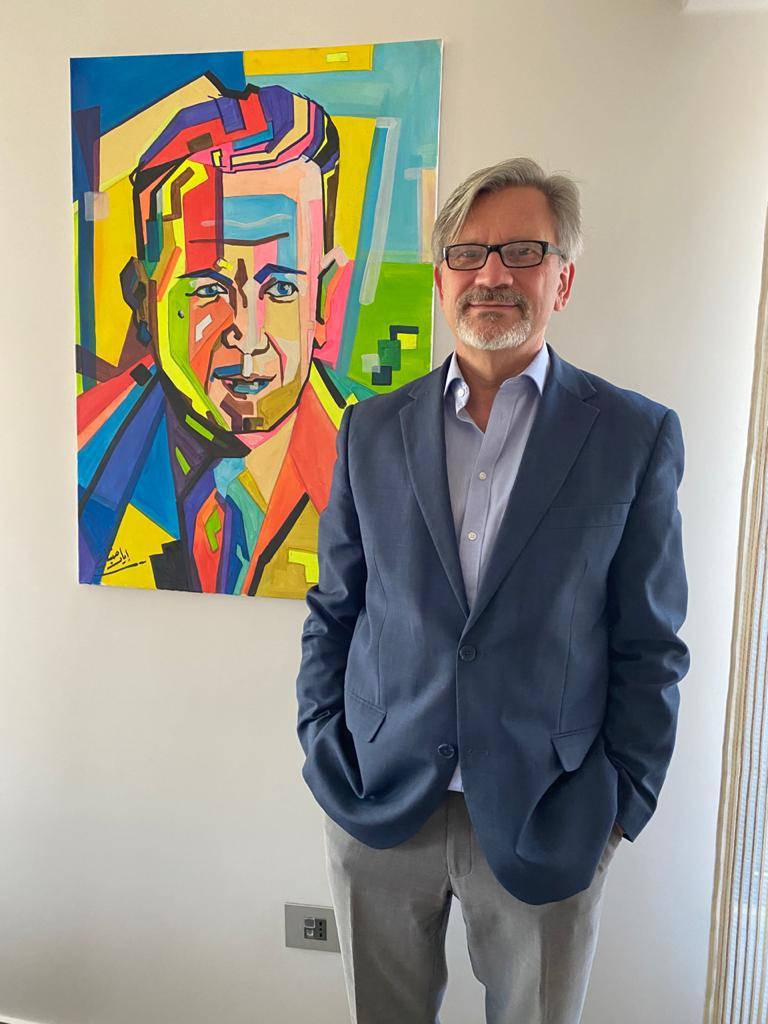Dominik Bartsch stands next to a portrait of Dag Hammarskjöld by Lyad Fanan, a Syrian artist currently living in the Za’atari refugee camp. Photograph courtesy of Dominik Bartsch.